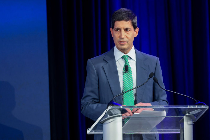 Kevin Warsh speaking at a podium.
