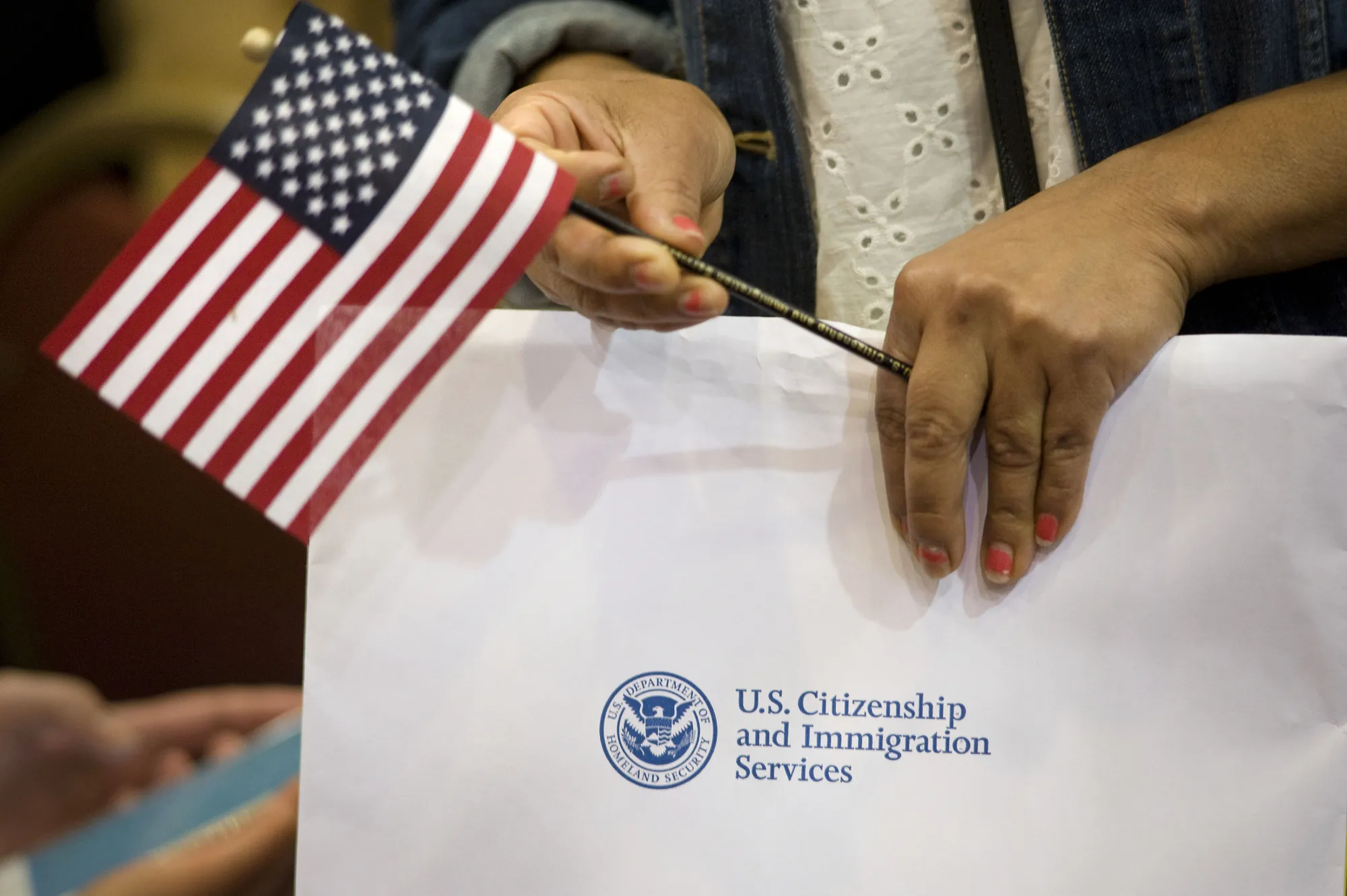 A woman holds an American flag and her papers during a naturalization ceremony in San Diego, California.