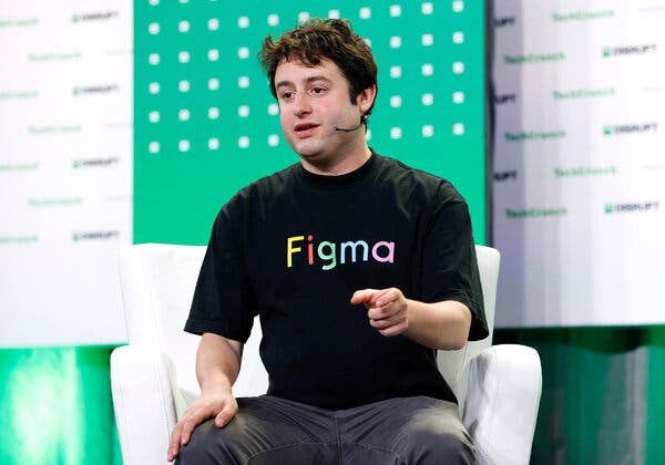 Dylan Field, wearing a black T-shift that says Figma, sits on a stage, gesturing as he talks. 