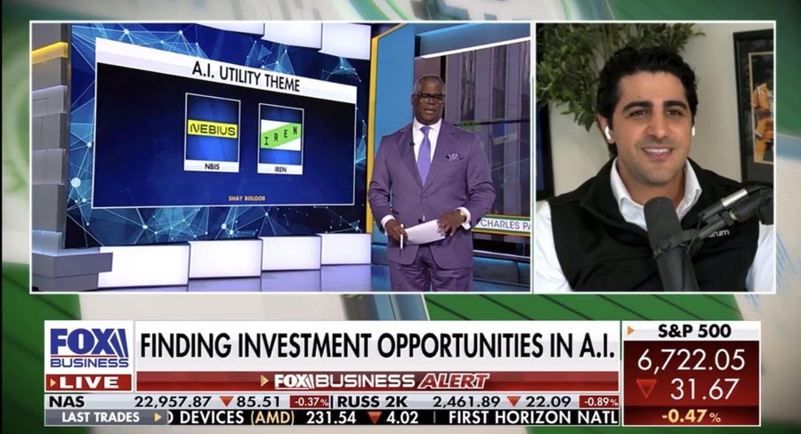 Split-screen image from Fox Business live broadcast showing a man in a purple suit speaking at a desk with microphone and papers next to a graphic titled AI Utility Theme displaying logos for WULF and another symbol with green and red indicators overlaid on stock market tickers including S and P 500 at 6222.05 up 0.31 percent and other indices like Dow at 42957.87 up 1.02 percent with network logos and timestamps visible