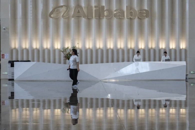 The reception area at Alibaba visitor center with two women at the reception desk and one woman walking past.