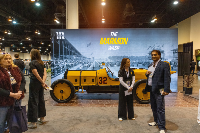People milling about the Wells Lamont booth, which features a large display of "The Marmon Wasp" race car.