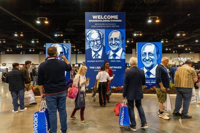 Shareholders and event-goers attend the Berkshire Hathaway 2026 annual meeting, with large banners featuring illustrations of Warren Buffett and Greg Abel.