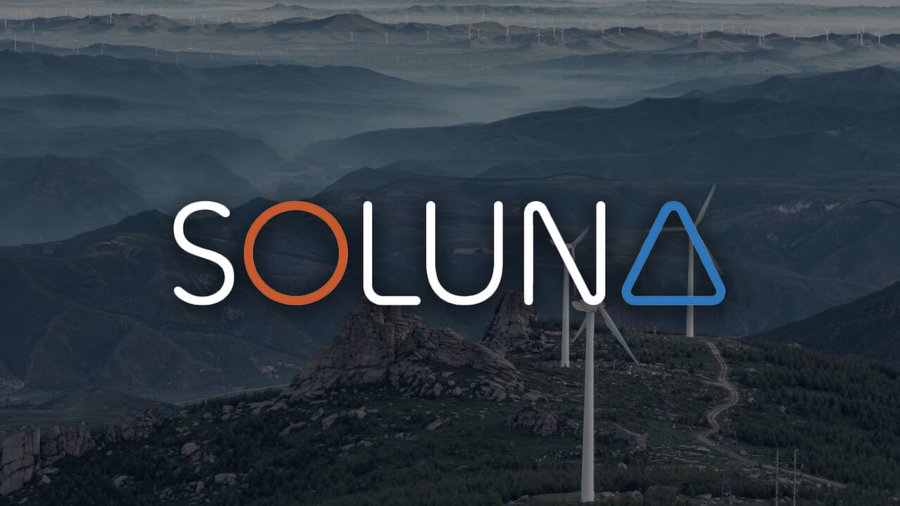 Mountainous landscape with layered ridges under a hazy sky features several white wind turbines on green hills in the foreground and a winding road leading into the distance. Prominent overlaid text reads SOLUNA in large blue and orange letters with a triangular symbol.
